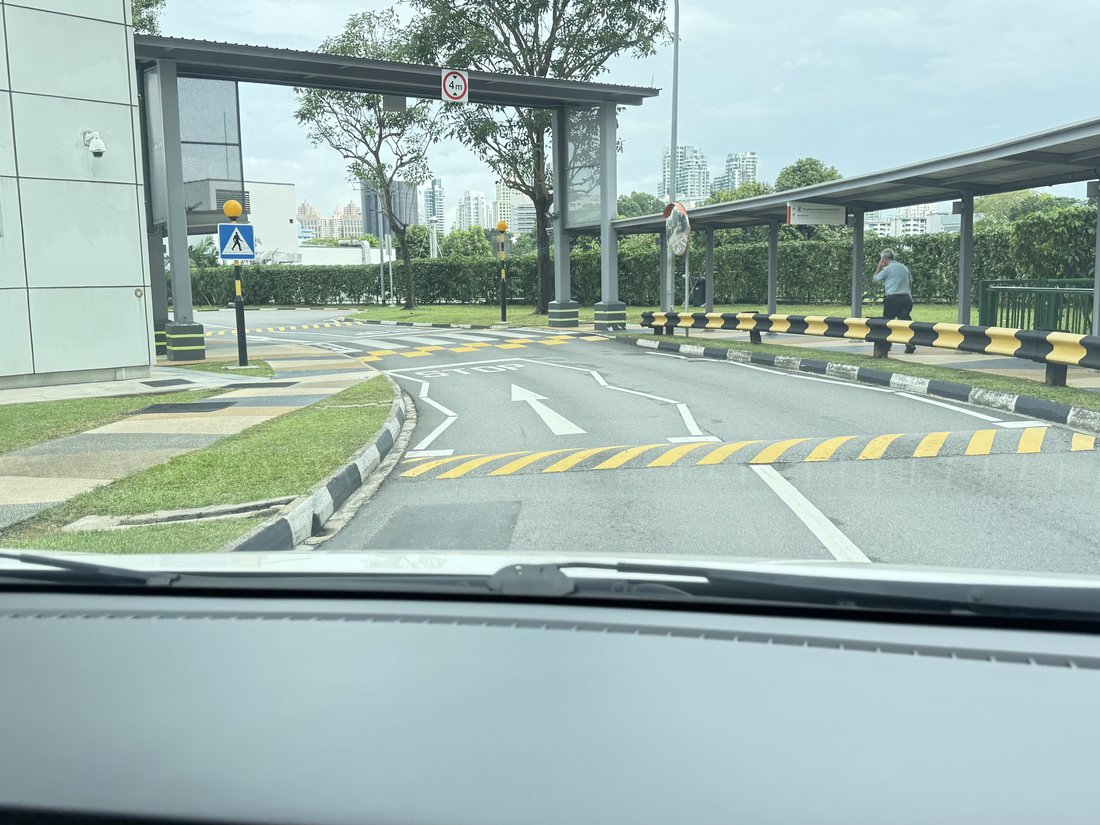 A road approach with yellow speed humps, STOP marking and chevrons before a raised crossing